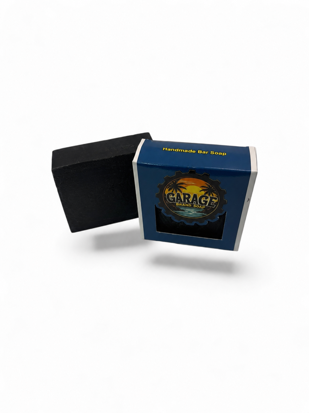 Garage Brand Soap handmade black bar soap in small batches, shown beside its blue retail box with tropical sunset branding.